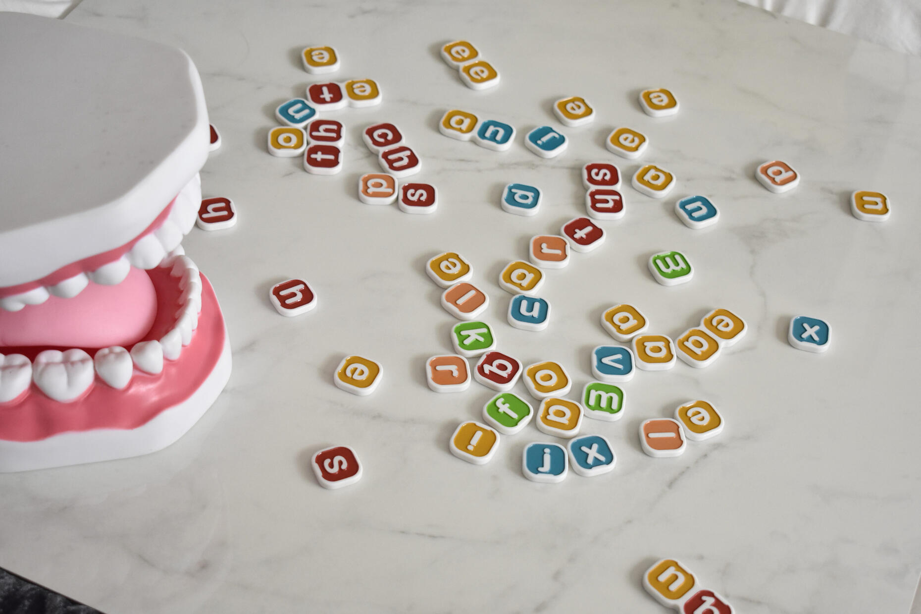 Scattered letter tiles next to a mouth model