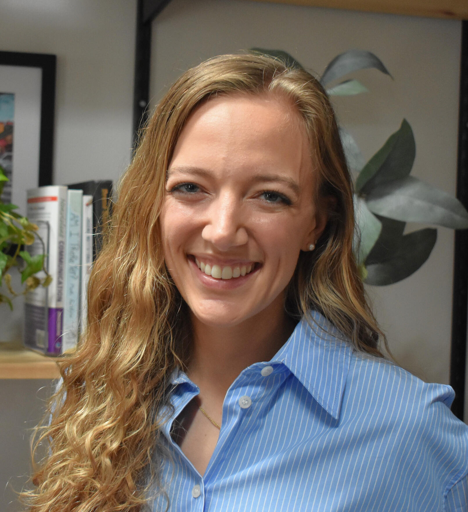 Rachel smiles at the camera in front of a shelf of books.